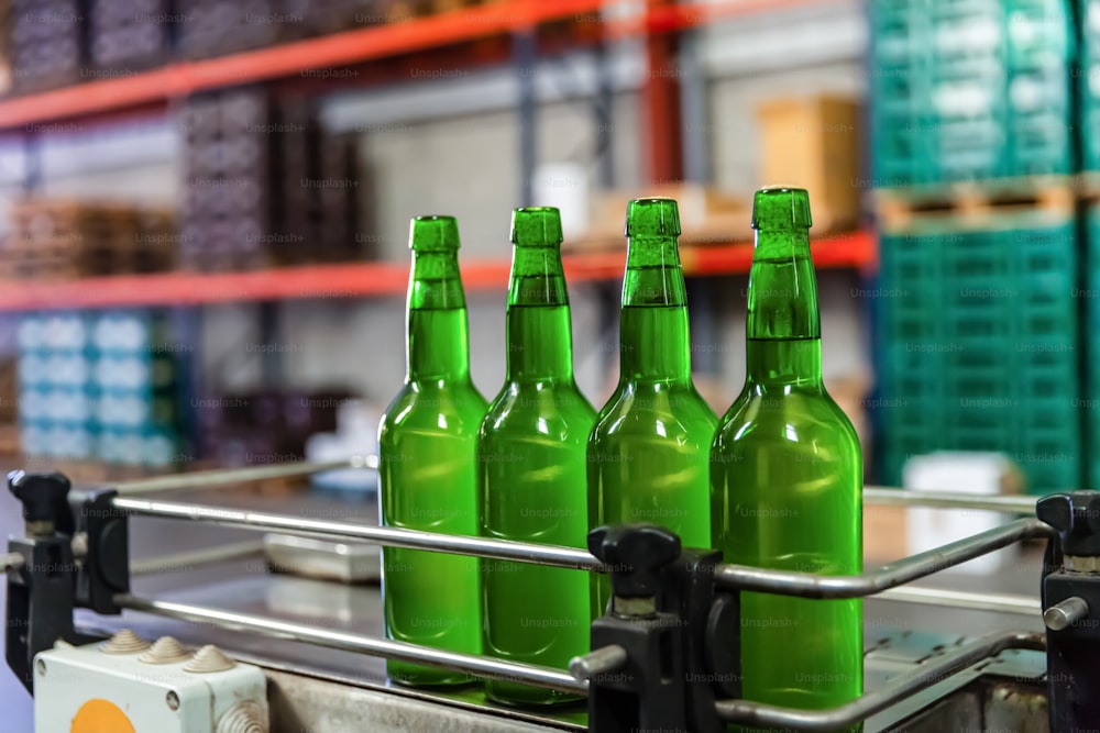 Four green glass bottles of apple cider on bottling line at factory