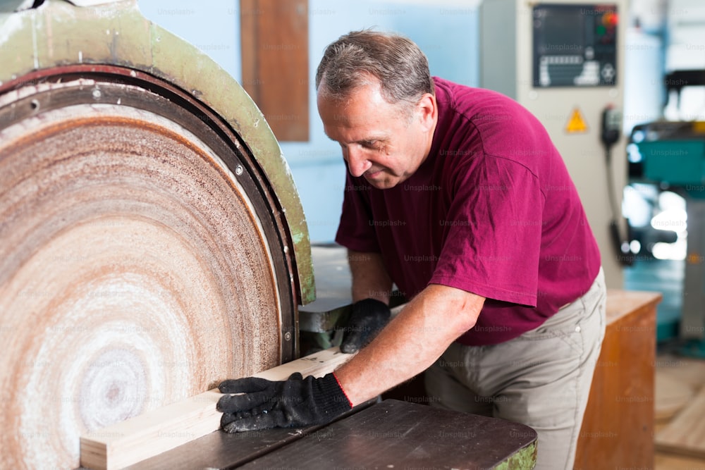 Carpenter handles wooden block on grinding machine