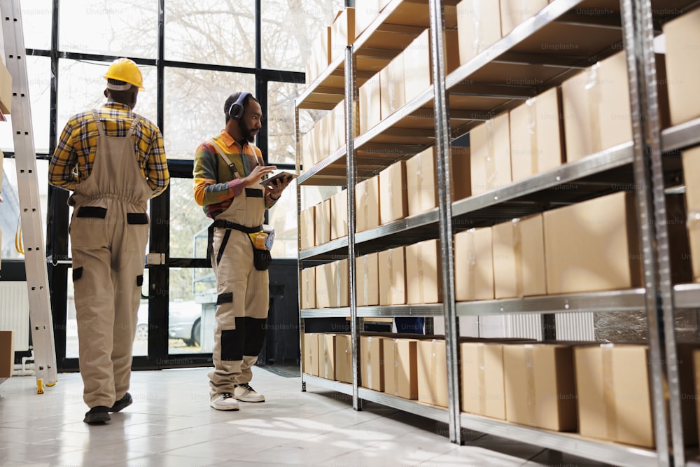 African american warehouse employee in headphones overseeing parcels security and maintenance. Post office shipment operator listening to music and working in storage room