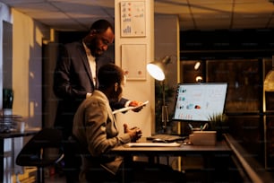 Corporate workers analyzing financial graphs report discussing company strategy late at night in startup office. Executive managers working at investment plan to increase business profit