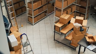 Empty storehouse space with stacks of cardboard boxes, small business concept with shelves and racks of stock merchandise. Products packed in packages used for shipment and delivery.
