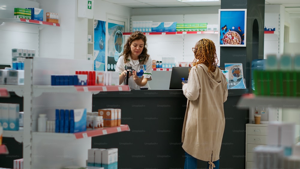 Medical worker scanning medicaments boxes at drugstore counter, helping clients to buy pharmaceutical products and pills. Employee working at pharmacy desk with vitamins supplements.