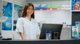 Asian pharmacist working in pharmaceutical drugstore shop, looking at prescription on computer. Analyzing medical treatment and supplements in pharmacy retail store, healthcare. Handheld shot.