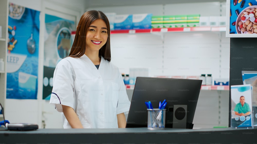 Asian pharmacist working in pharmaceutical drugstore shop, looking at prescription on computer. Analyzing medical treatment and supplements in pharmacy retail store, healthcare. Handheld shot.