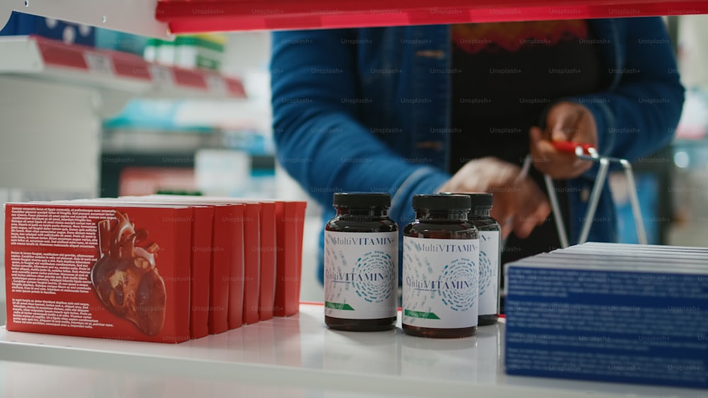 Client afro-américain prenant des pilules sur les étagères de la pharmacie, cherchant à acheter des médicaments et des vitamines. Femme achetant des médicaments sur ordonnance et des médicaments pour guérir la maladie. Gros plan.
