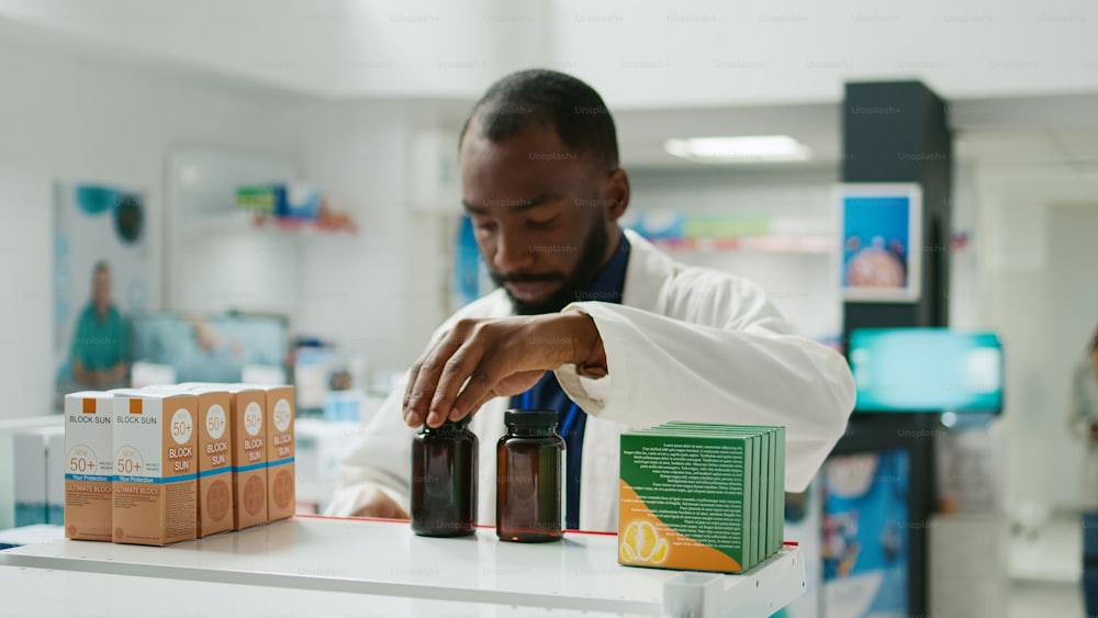 남성 전문가는 약국 선반에 의약품과 의약품을 보관하고 고객을 돕기 위해 알약과 비타민 상자를 넣습니다. 의약품, 의료 분야에서 일하는 청년.