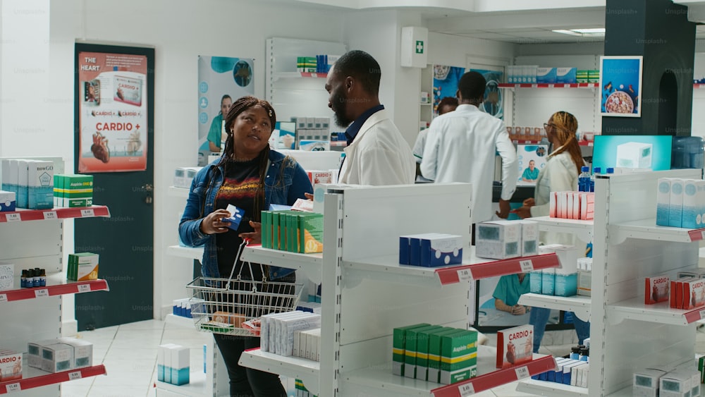 Health specialist helping client with boxes of medicine, giving medical advice to people in pharmacy. Medic talking to customer about treatment and pharmaceutical products. Tripod shot.