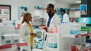 Male doctor recommending healthcare products to client, showing medicaments and supplements to cure disease. Young woman talking to specialist about treatment, buying box of pills.