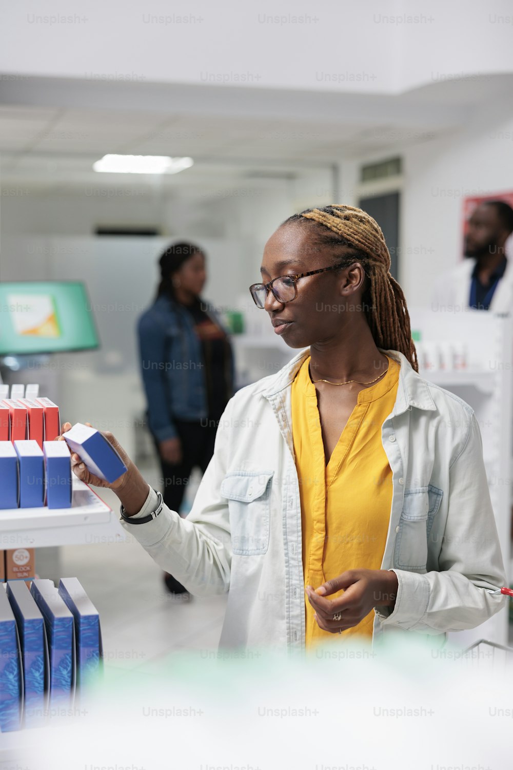African american drugstore buyer choosing medications in pharmacy store, reading instruction on tablets package. Young woman buying pills, pharmaceutical business, medicaments retail concept