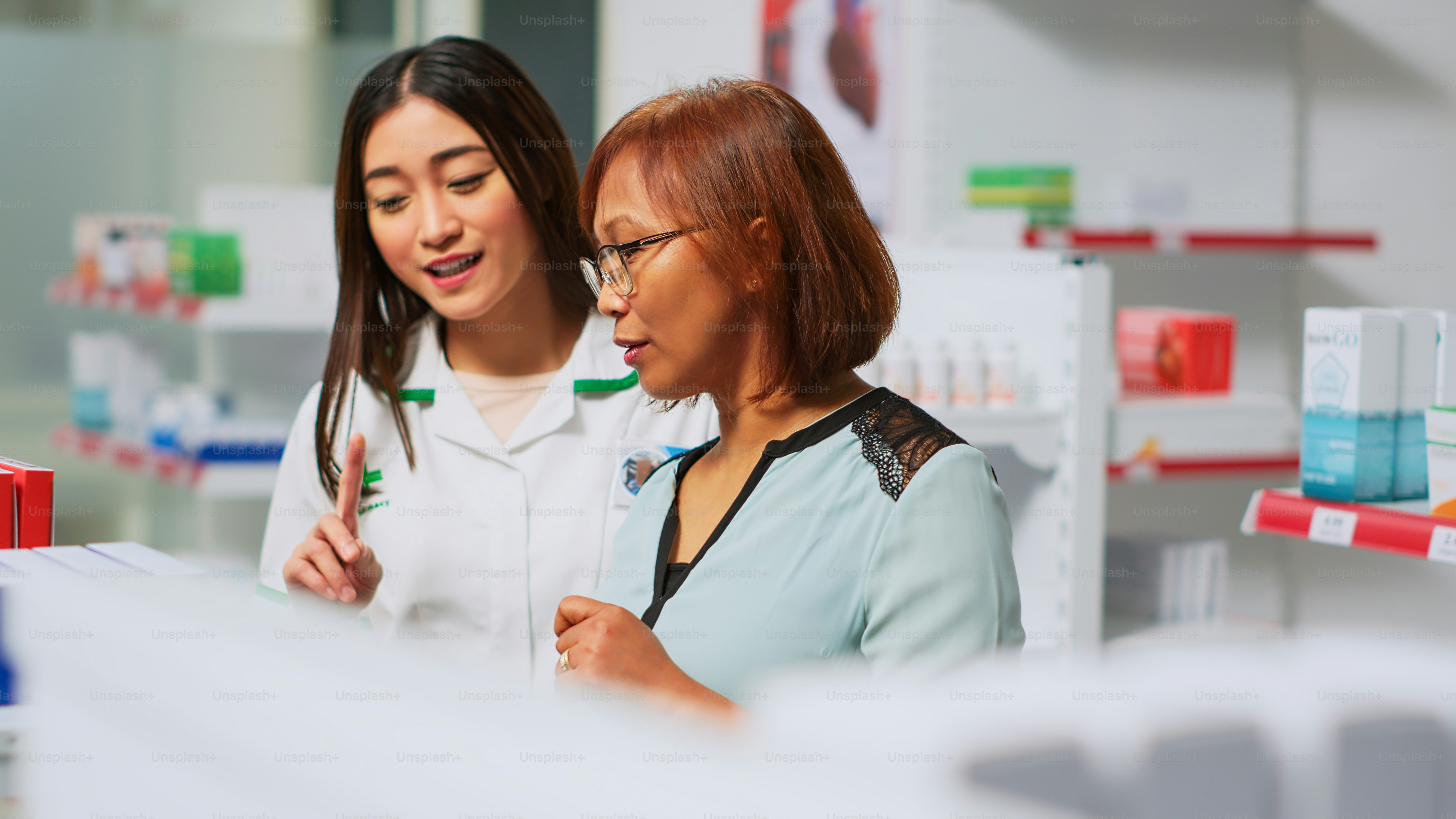 Healthcare specialist explaining drugs treatment to person in drugstore, showing bottle of medicine against disease. Medical worker talking to female client about vitamins and pills. Handheld shot.