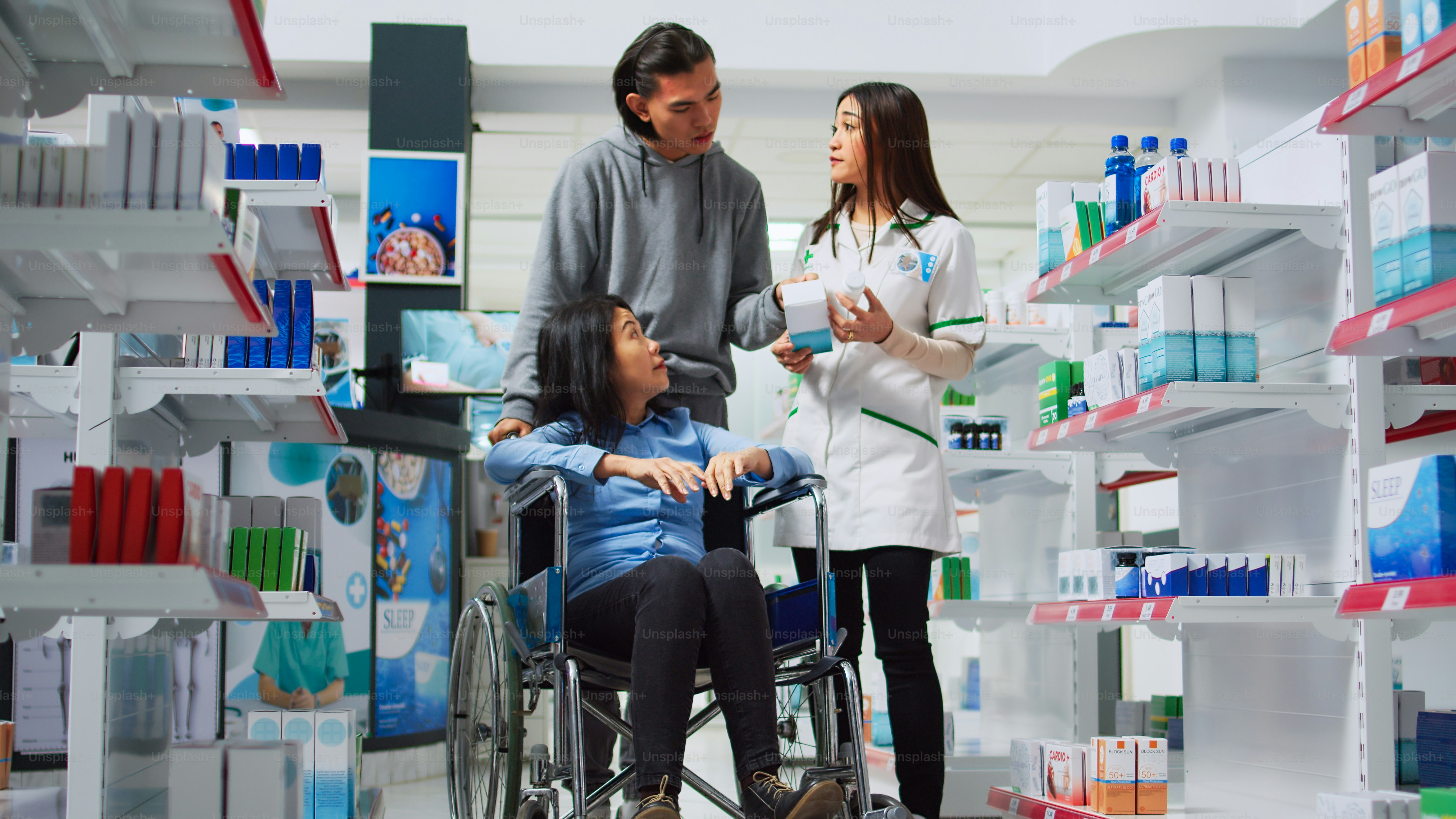 Pharmaceutical worker giving pills box to customer in wheelchair, male caretaker helping person with disabiity. Pharmacist giving medicine pills to client and social worker in drugstore.