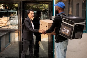 Food delivery service courier giving customer pizza order. African american man delivering pizzeria takeaway meal, company employee taking fastfood packages stack near office building
