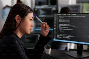 Programmeur informatique asiatique pensif pensant au développement de scripts html, brainstorming idées pour créer du code html. Développeur de logiciels informatiques travaillant sur serveur de base de données dans une société de bureau de logiciels