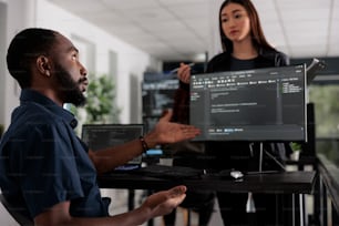 Développeurs d’applications travaillant sur une fenêtre temrinal avec script html et écrivant du code serveur sur ordinateur, assis dans une salle de big data. Interface utilisateur de programmation d’ingénieur système dans une agence de développement occupée.