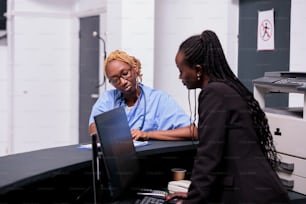 Equipe médica afro-americana analisando relatório de check-up com suporte de seguro de paciente em papéis. Enfermeira e recepcionista atuando em consultas de check-up na recepção do hospital, assistência médica.