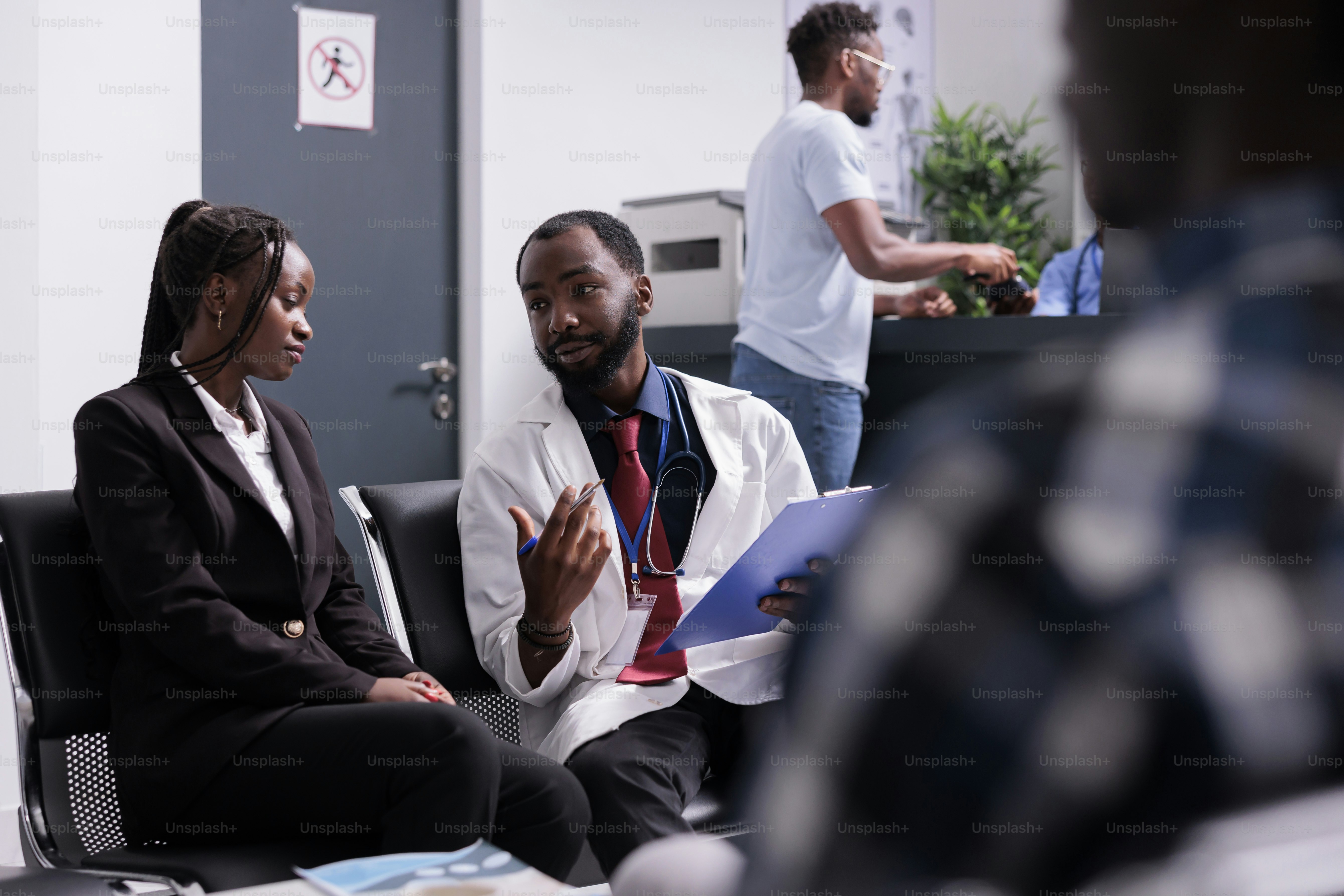 African american doctor and person at checkup visit consultation talking about healthcare and disease. Specialist consulting woman in waiting room area at health center lobby, medicare recovery.