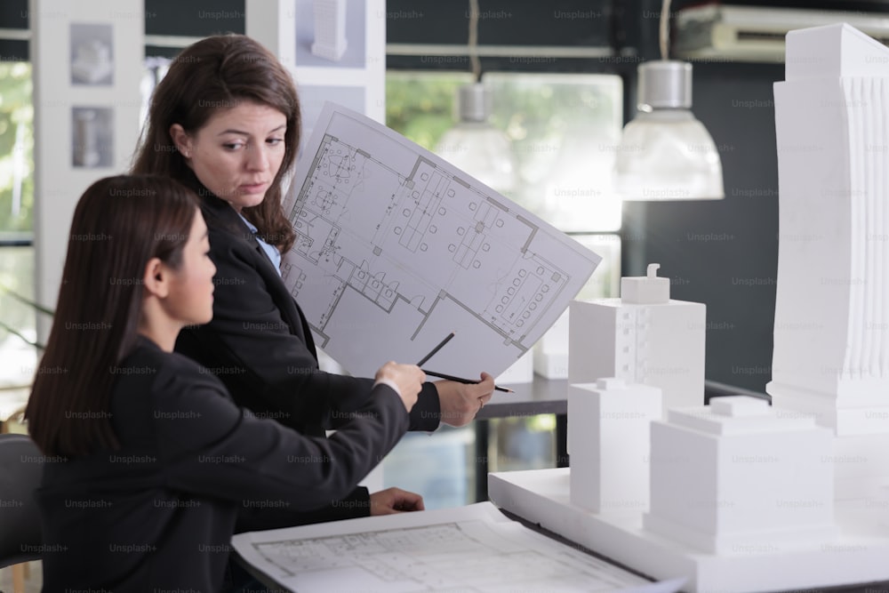 Architekt und Ingenieur halten einen Bauplan in der Hand, diskutieren die Skizze eines Bauprojekts und arbeiten mit CAD im Coworking Space. Mitarbeiter im Architekturbüro schauen sich gemeinsam CAD an.