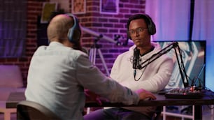 African american famous influencer and guest blogger talking on internet broadcast with sound equipment in home studio. Two men talking in online podcast episode recording for social media channel.