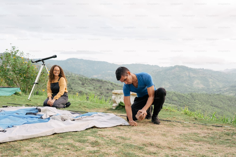 a man and a woman setting up a tarp on a mountain