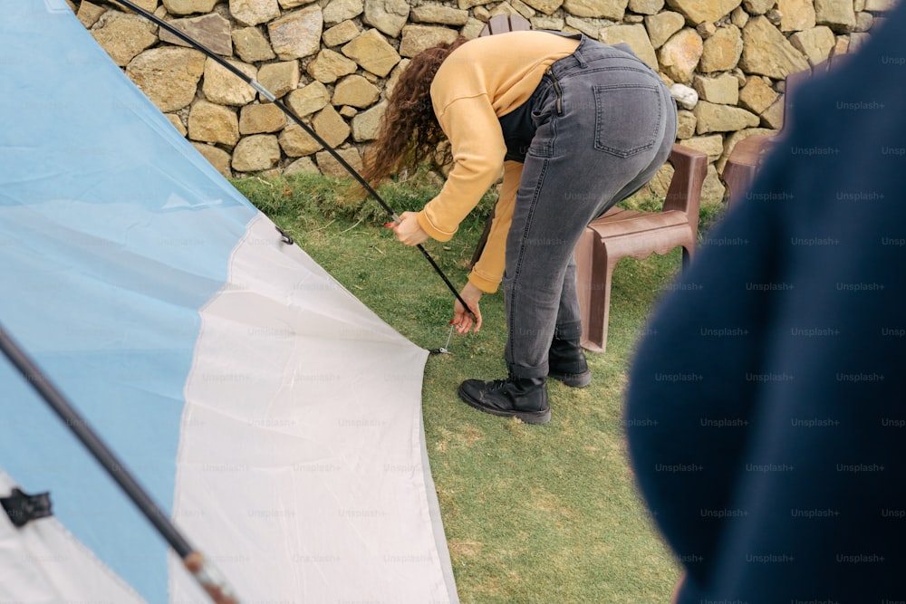 a woman bending over a blue and white umbrella