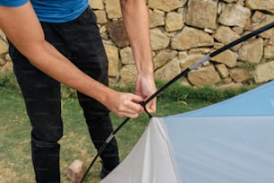 a man holding a blue and white umbrella next to a stone wall