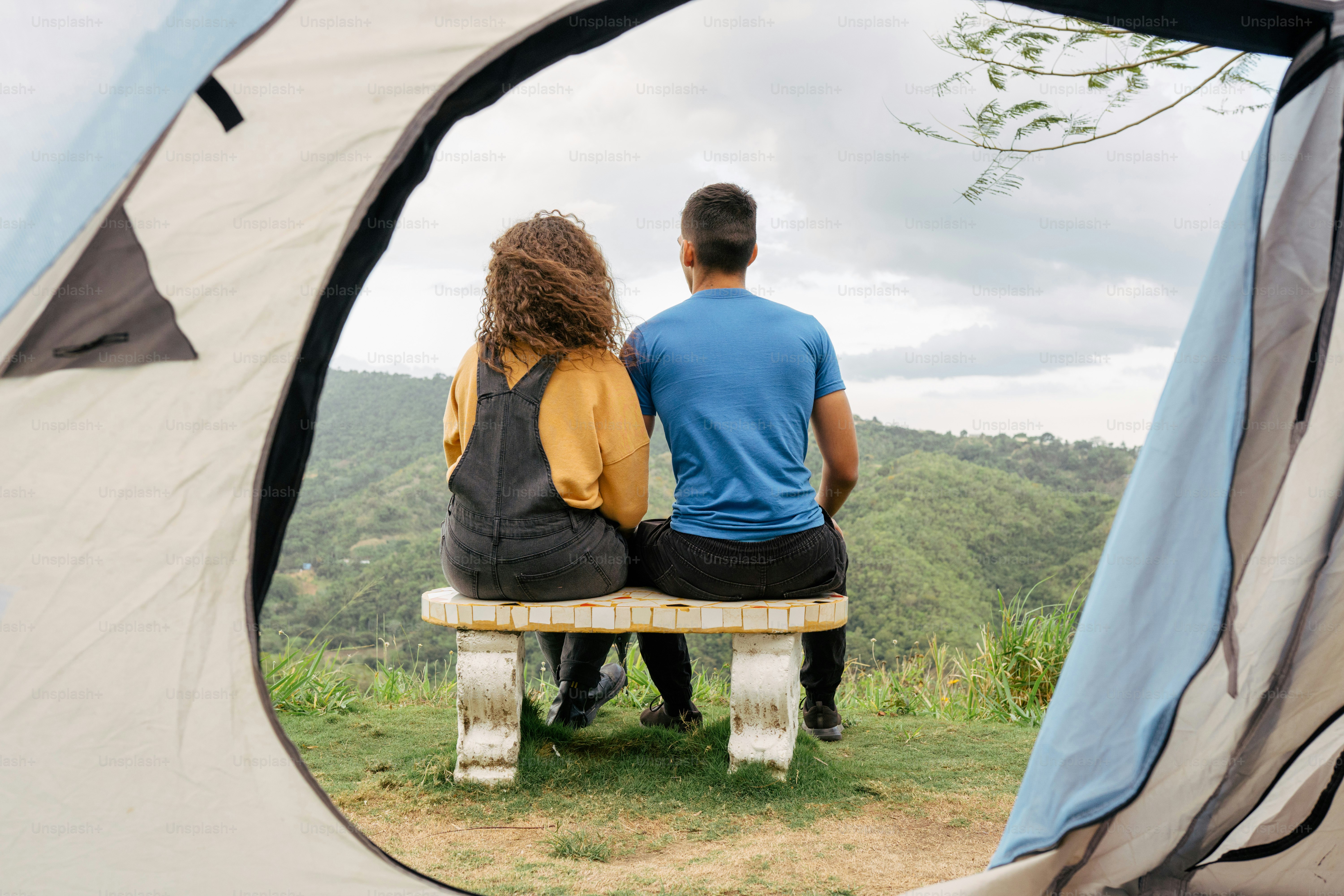 um homem e uma mulher sentados em um banco na frente de uma tenda