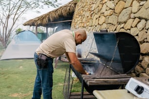 Un uomo in piedi sopra una griglia per barbecue in un campo