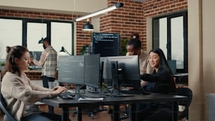 Ingegnere del software che digita il codice sorgente sulla tastiera del computer mentre i colleghi si siedono alla scrivania per il progetto di gruppo. Sviluppatore di app che lavora in una startup IT che fa cloud computing online.