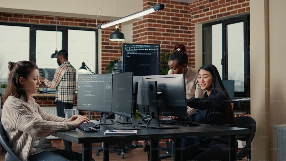 ソフトウェアエンジニアがコンピューターのキーボードでソースコードを入力し、同僚がグループプロジェクトのために机に座っています。オンラインクラウドコンピューティングを行うスタートアップ企業で働くアプリ開発者。