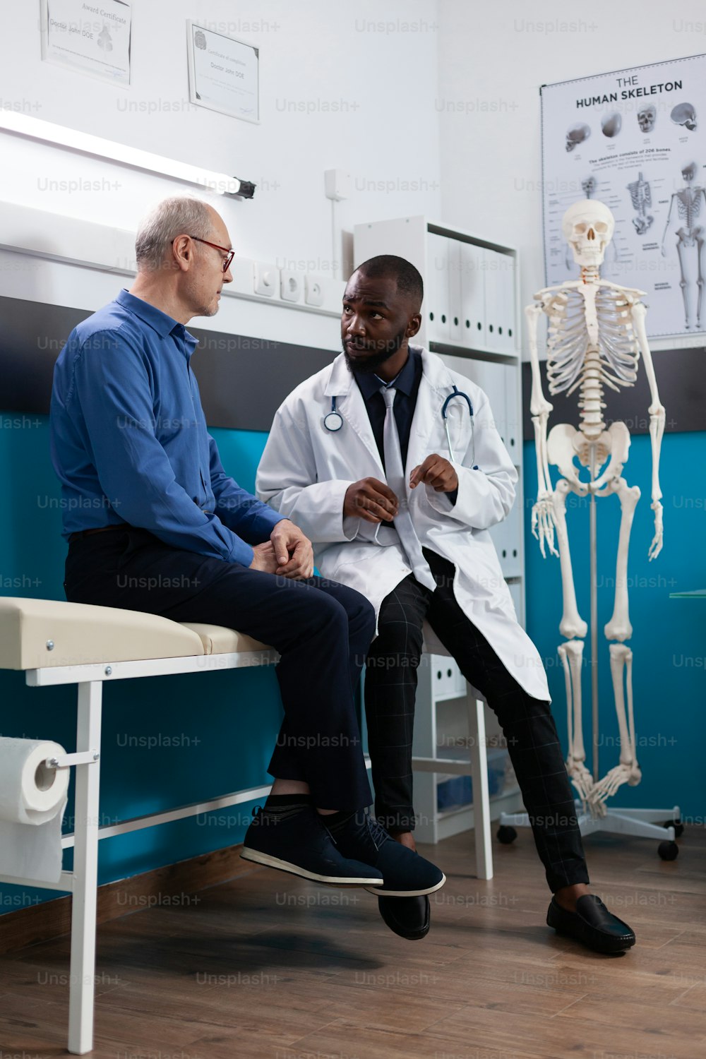 Retired old man discussing sickness symptoms to specialist therapist during medical appointment in hospital office. Physician doctor explaining disease diagnosis working at healthcare treatment