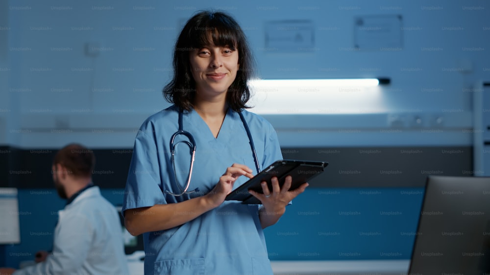 Portrait d’une infirmière sérieuse travaillant de nuit dans le bureau de l’hôpital tout en tapant expertise médicale sur ordinateur. Adjoint au médecin planifiant un traitement médicamenteux pour aider à guérir la maladie du patient.
