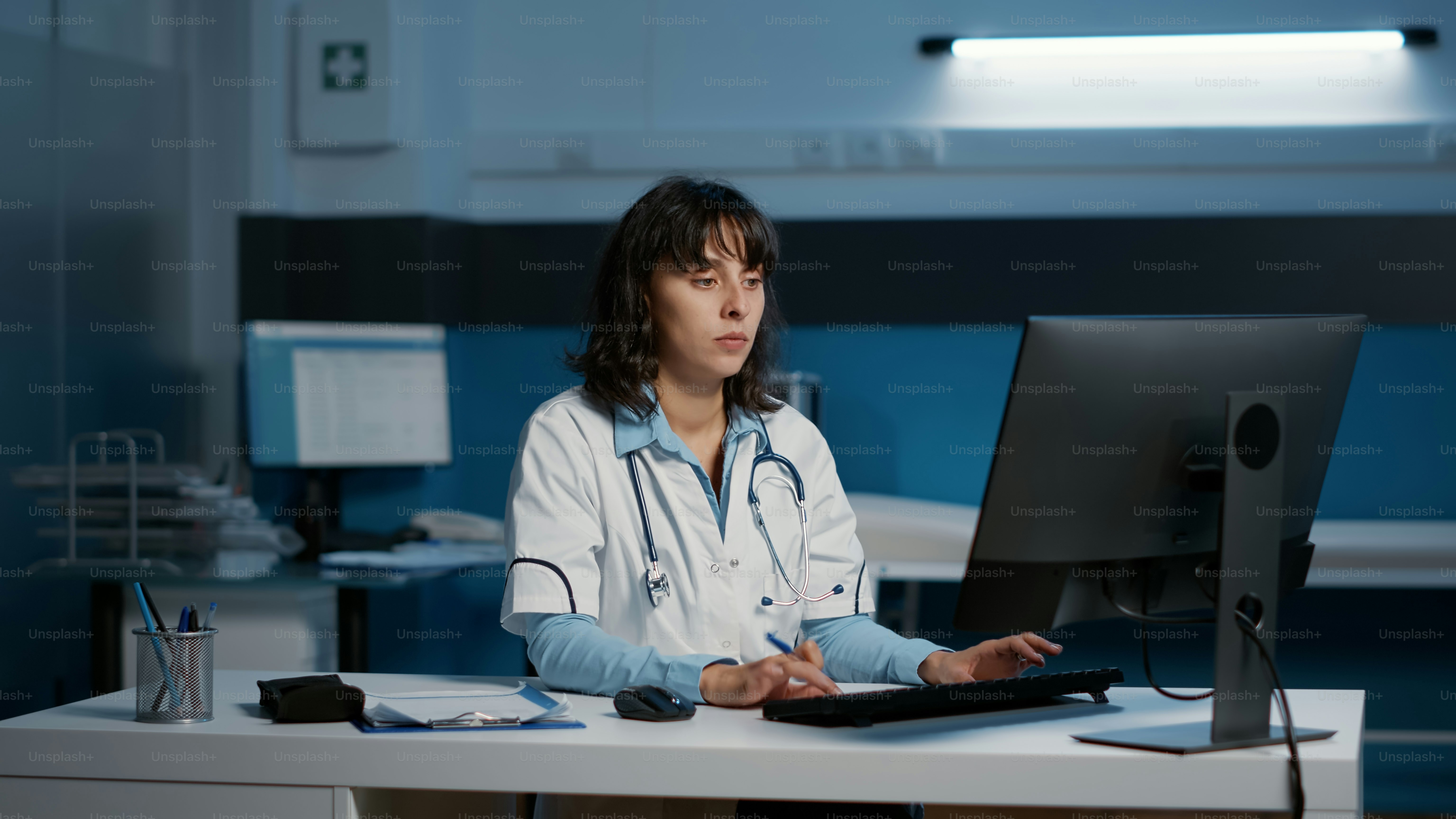 Allgemeinmediziner, der das Fachwissen des Patienten analysiert, den medizinischen Bericht auf dem Computer eintippt, während er stundenlang im Krankenhausbüro arbeitet. Arzt, Arzt, der eine Gesundheitsbehandlung zur Heilung von Krankheiten plant