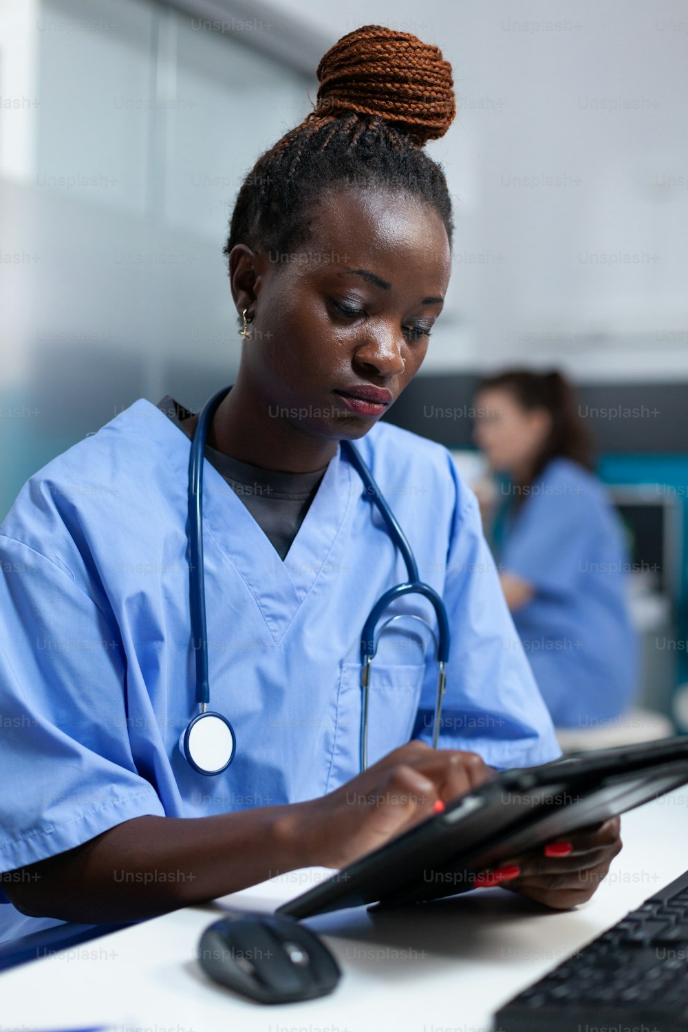 Enfermera afroamericana en uniforme médico analizando la prescripción de enfermedad en una tableta que trabaja en la oficina del hospital. Asistencia médica para monitorear el tratamiento de la salud de escritura de la enfermedad