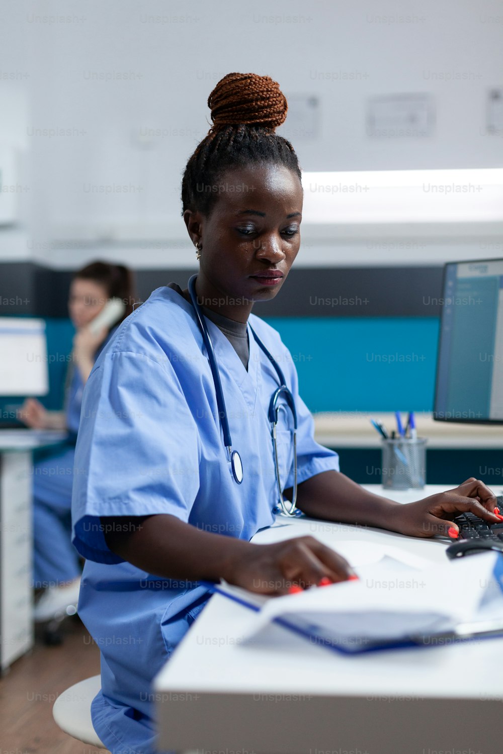 African american practitioner nurse analyzing sickness expertise on medical documents working in hospital office. Physician asisstant with stethoscope checking illness results sitting at desk