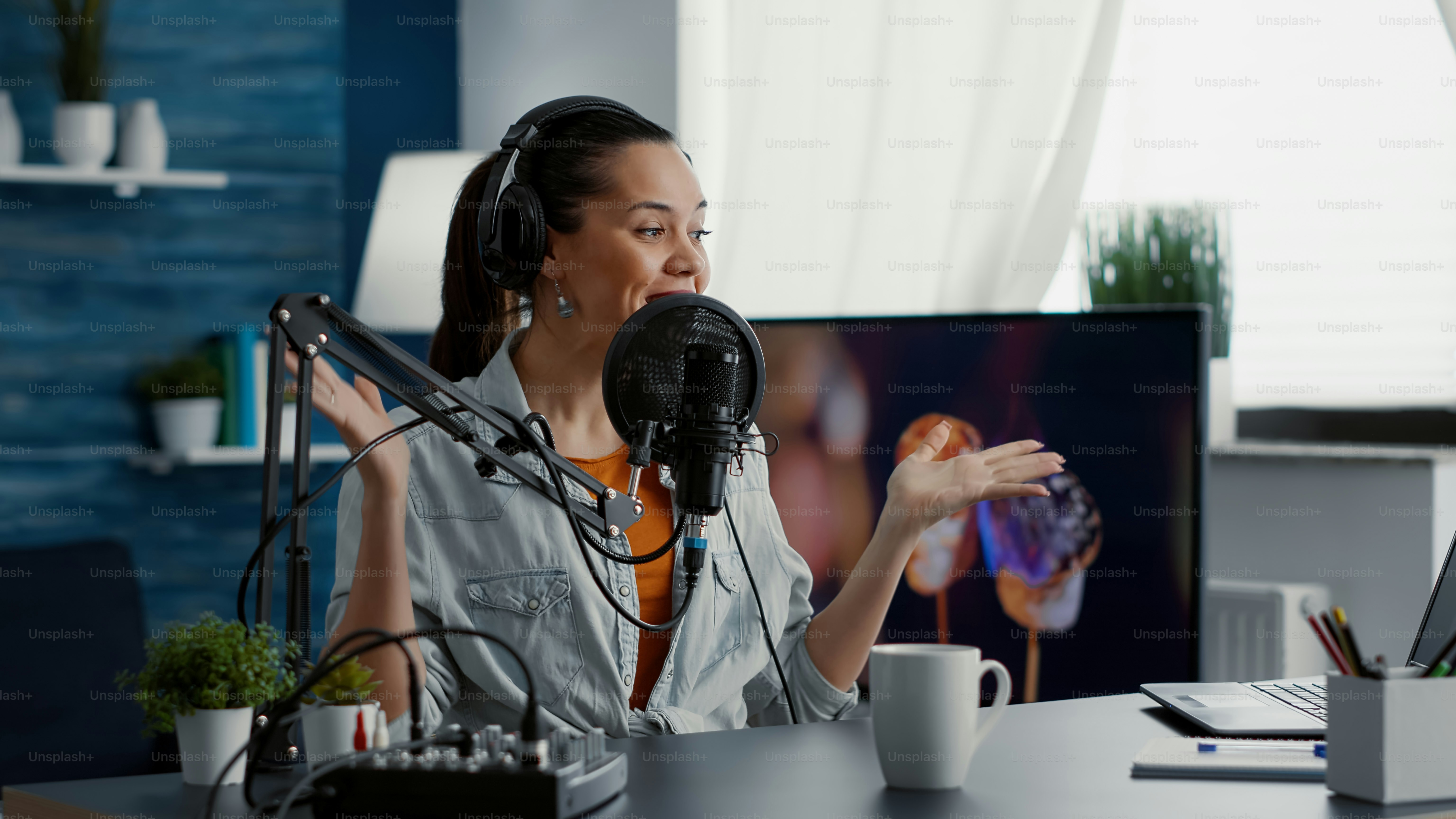 Happy internet live radio morning show host talking to audience on microphone. Joyful social media content creator hosting online broadcast while speaking to public in modern living room studio.