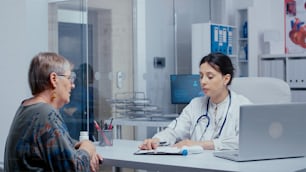 Doctor doing a temperature check in office to senior retired woman patient. Healthcare in modern hospital or private clinic, disease prevention and consultation in medic office treatment medication diagnosis expertise