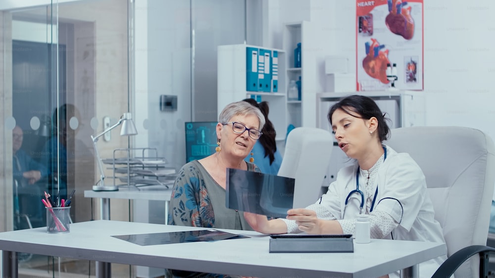 Doctor using x-rays to consult with patient in modern private healthcare hospital. Healthcare in modern hospital or private clinic, disease prevention and consultation in medic office treatment medication diagnosis expertise