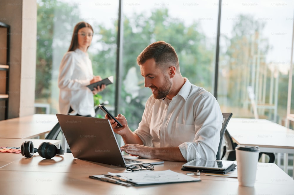 Successful deal. Using laptop. Man and woman are working in the modern office together.