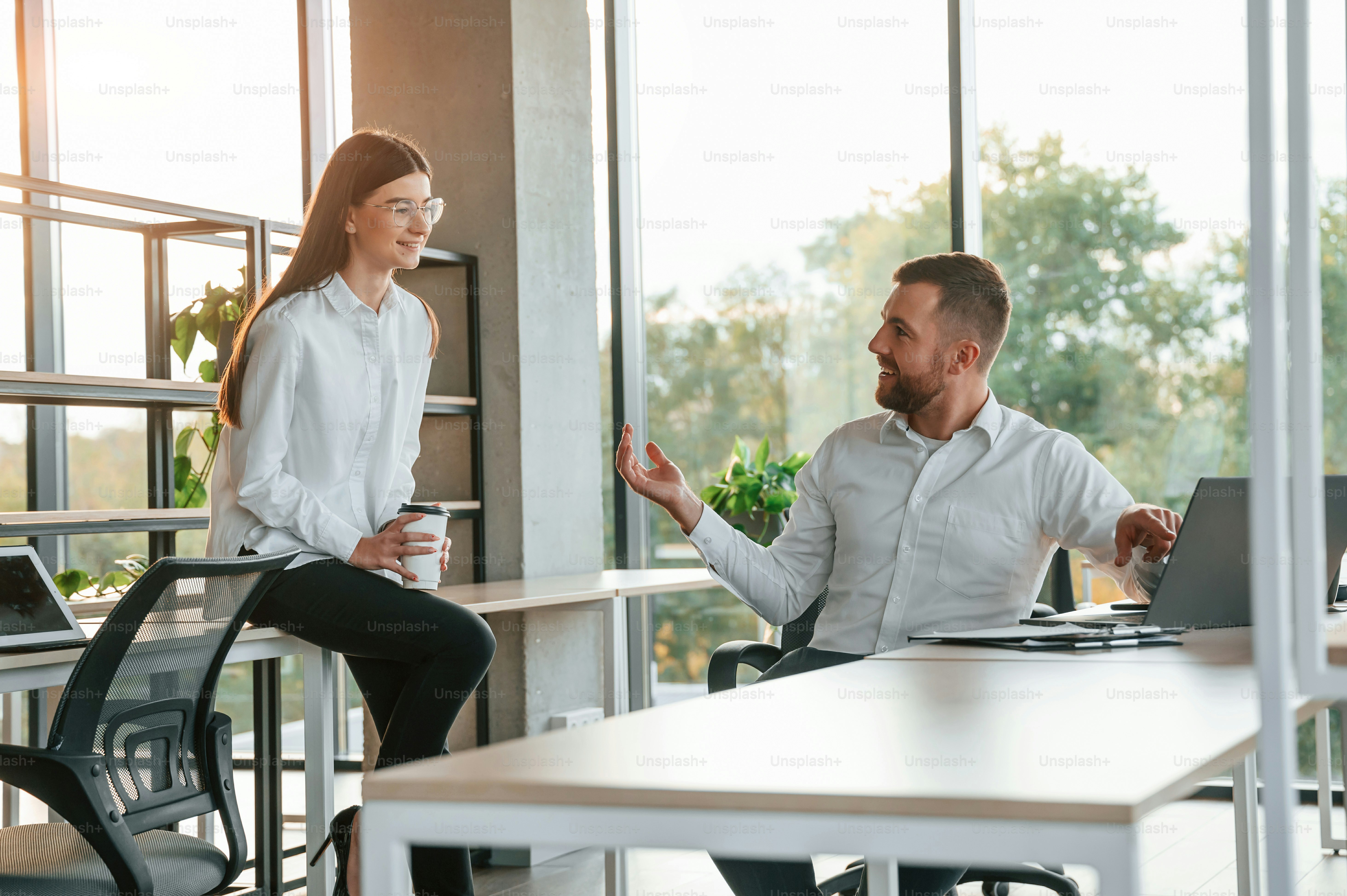 Avere una conversazione. L'uomo e la donna lavorano insieme nell'ufficio moderno.