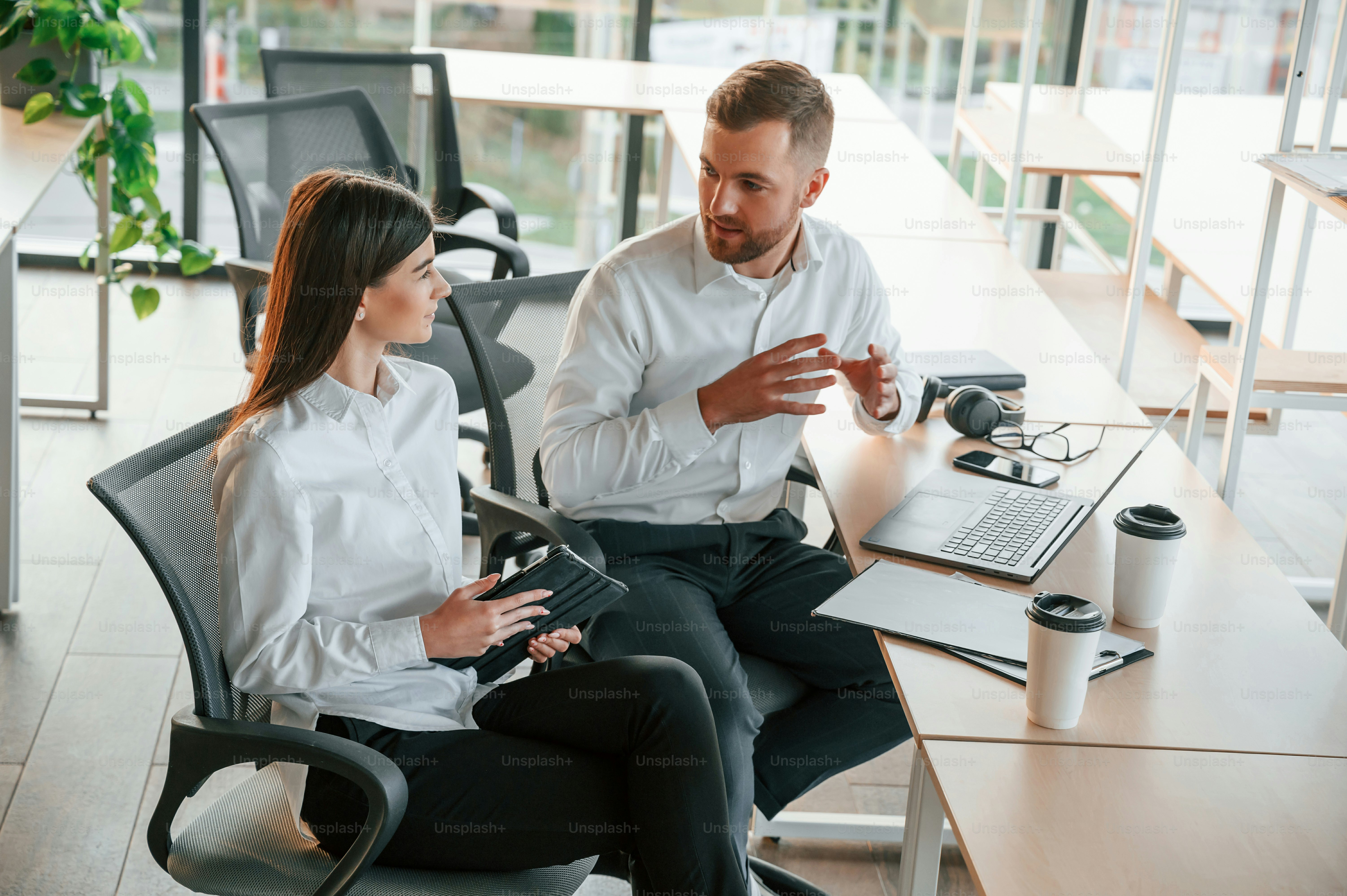 Seduto al tavolo con il computer portatile. L'uomo e la donna lavorano insieme nell'ufficio moderno.