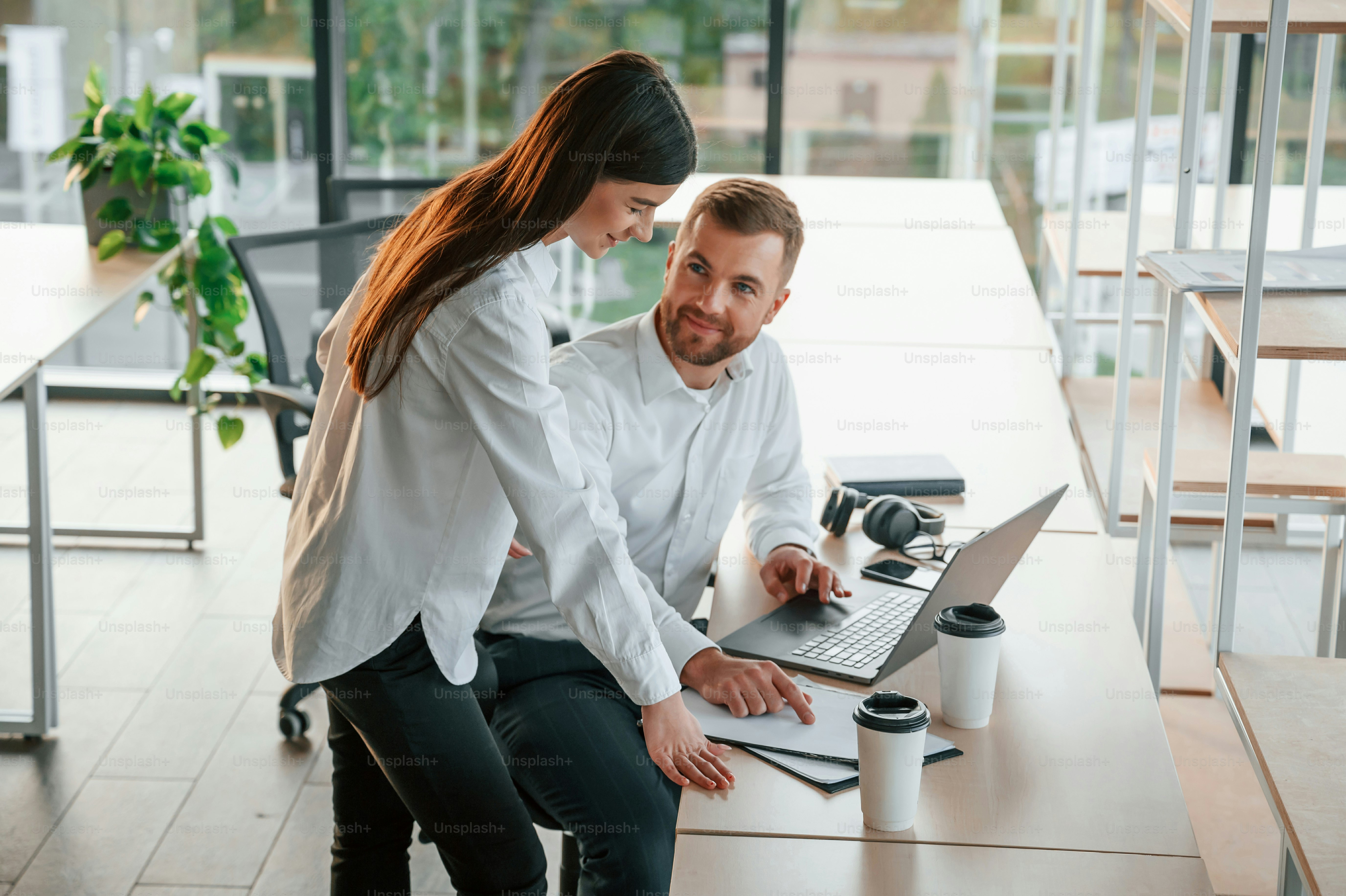 Utilizzando il computer portatile. L'uomo e la donna lavorano insieme nell'ufficio moderno