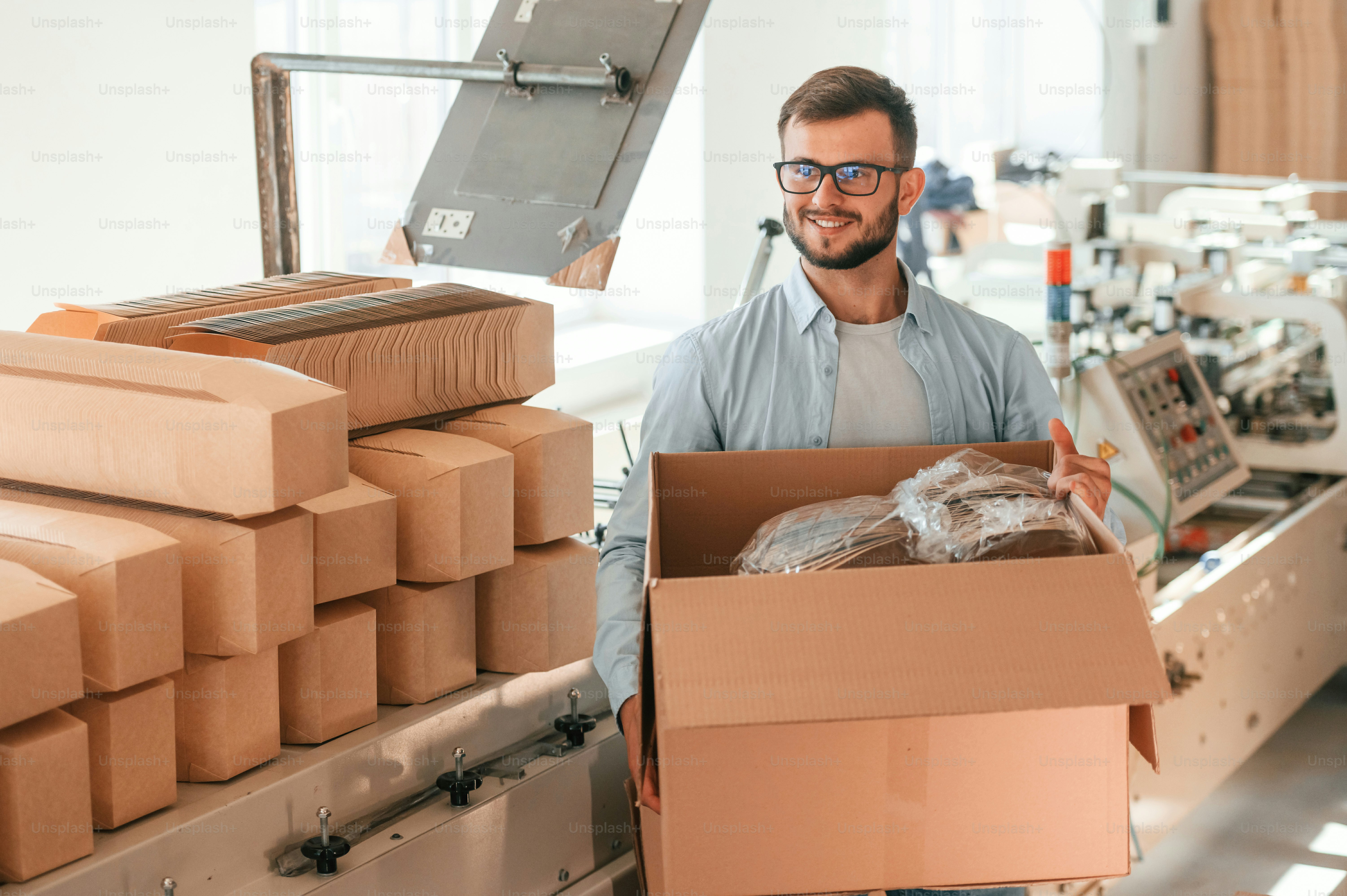 Holding the box. Print house worker in white clothes is indoors.
