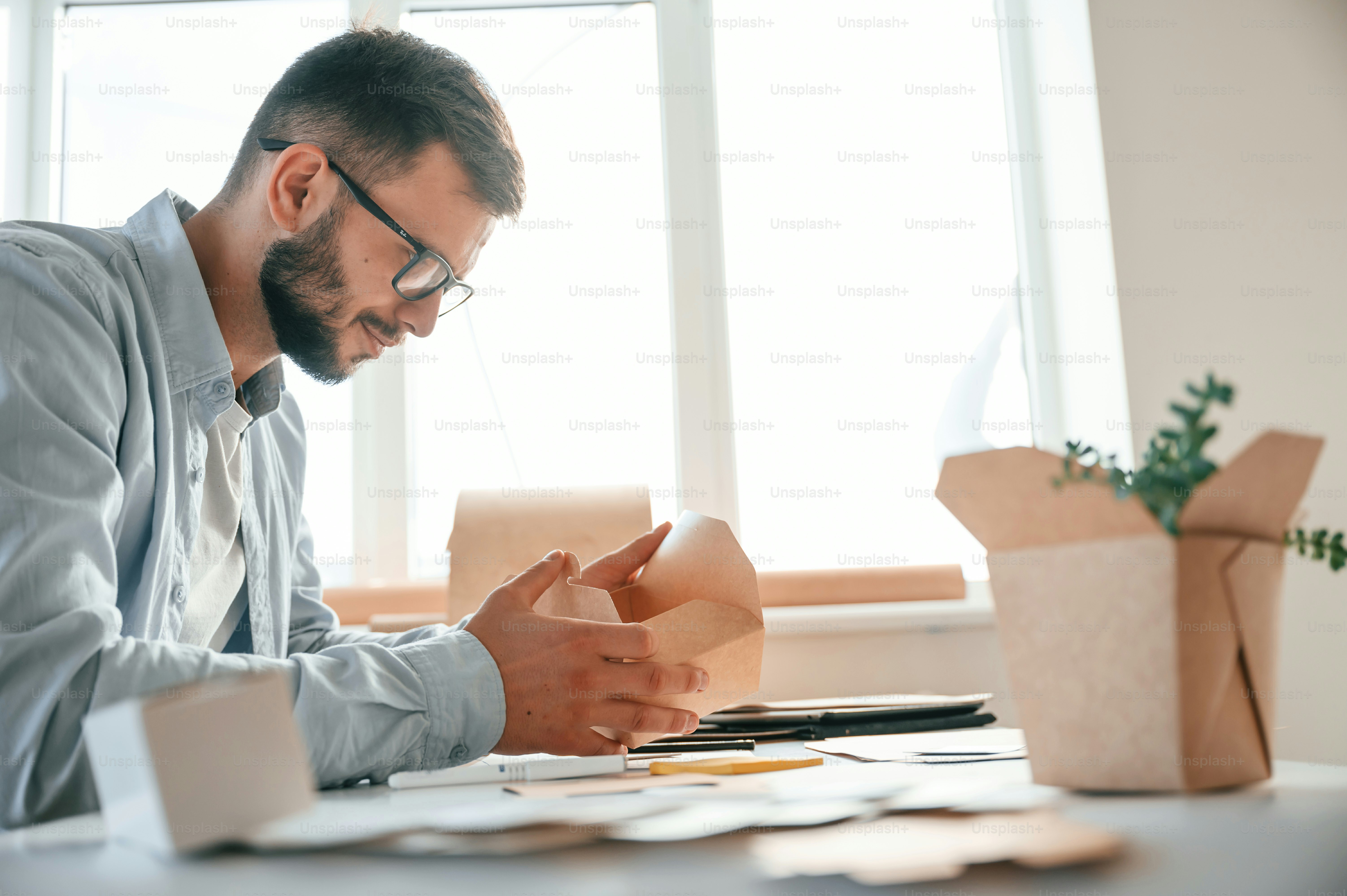 Holding little wooden box. Print house worker in white clothes is indoors.