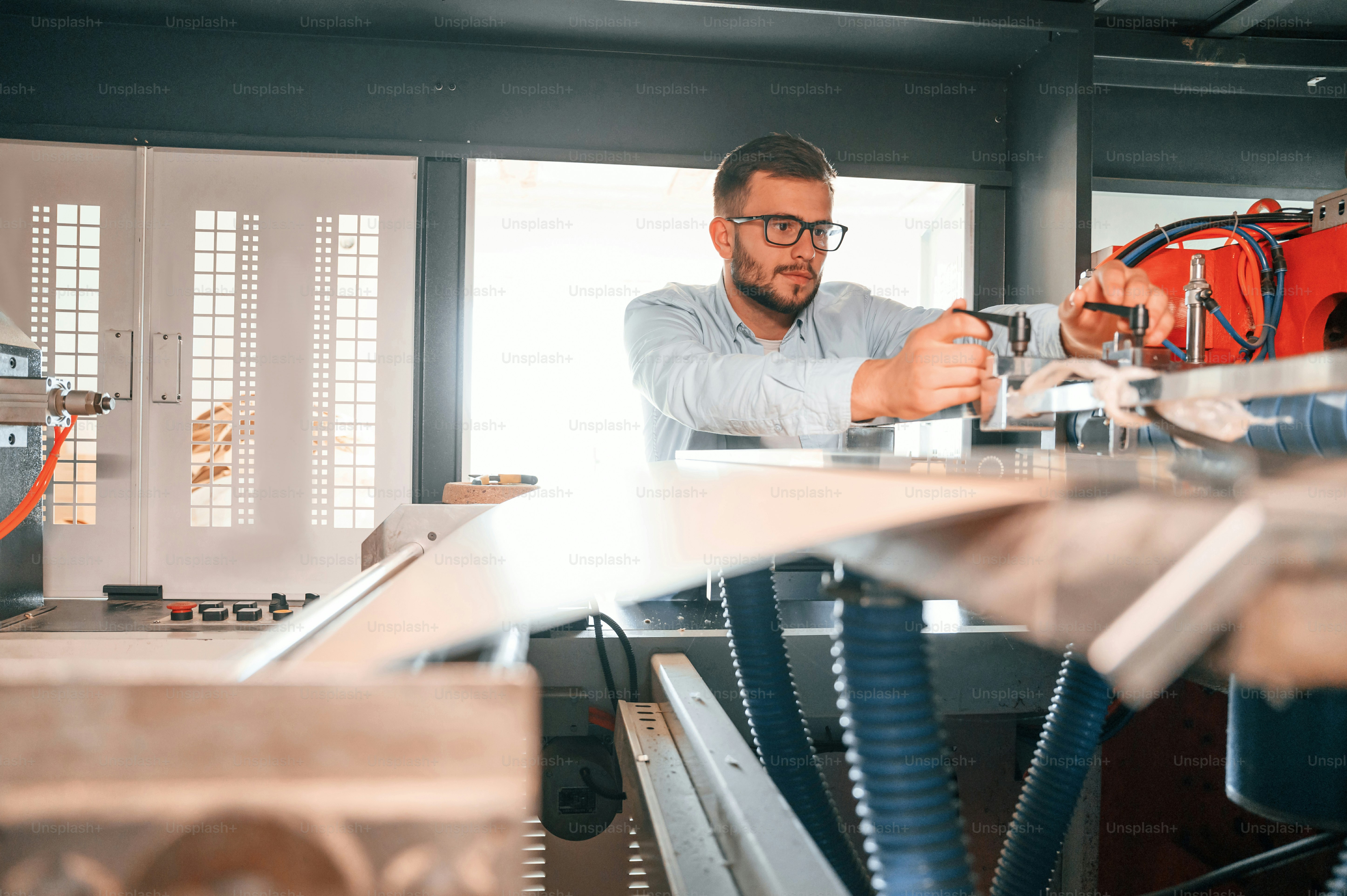 Sheet cutting machine. Operating device. Print house worker in white clothes is indoors.