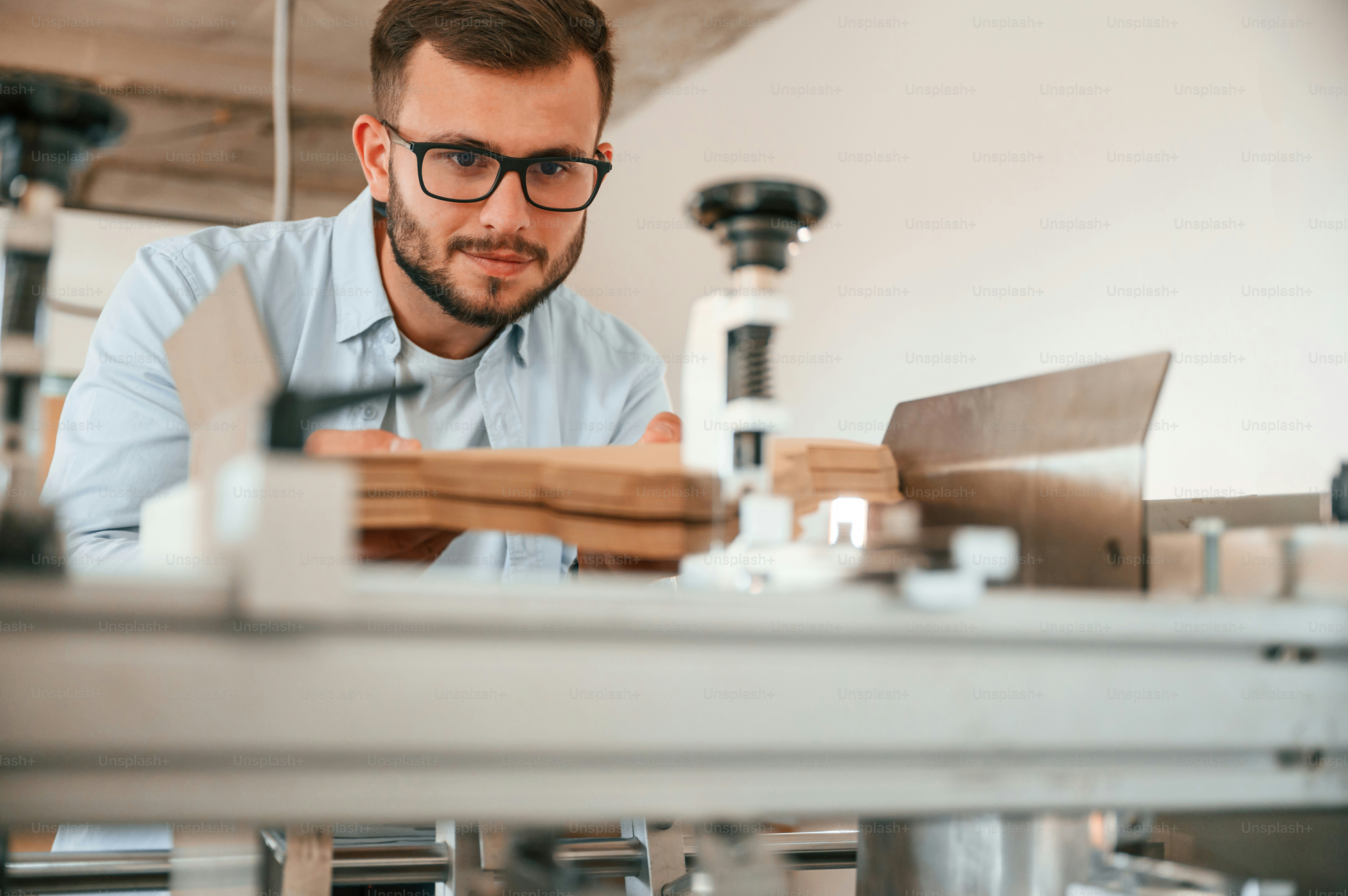 Using the cutting machine. Print house worker in white clothes is indoors.