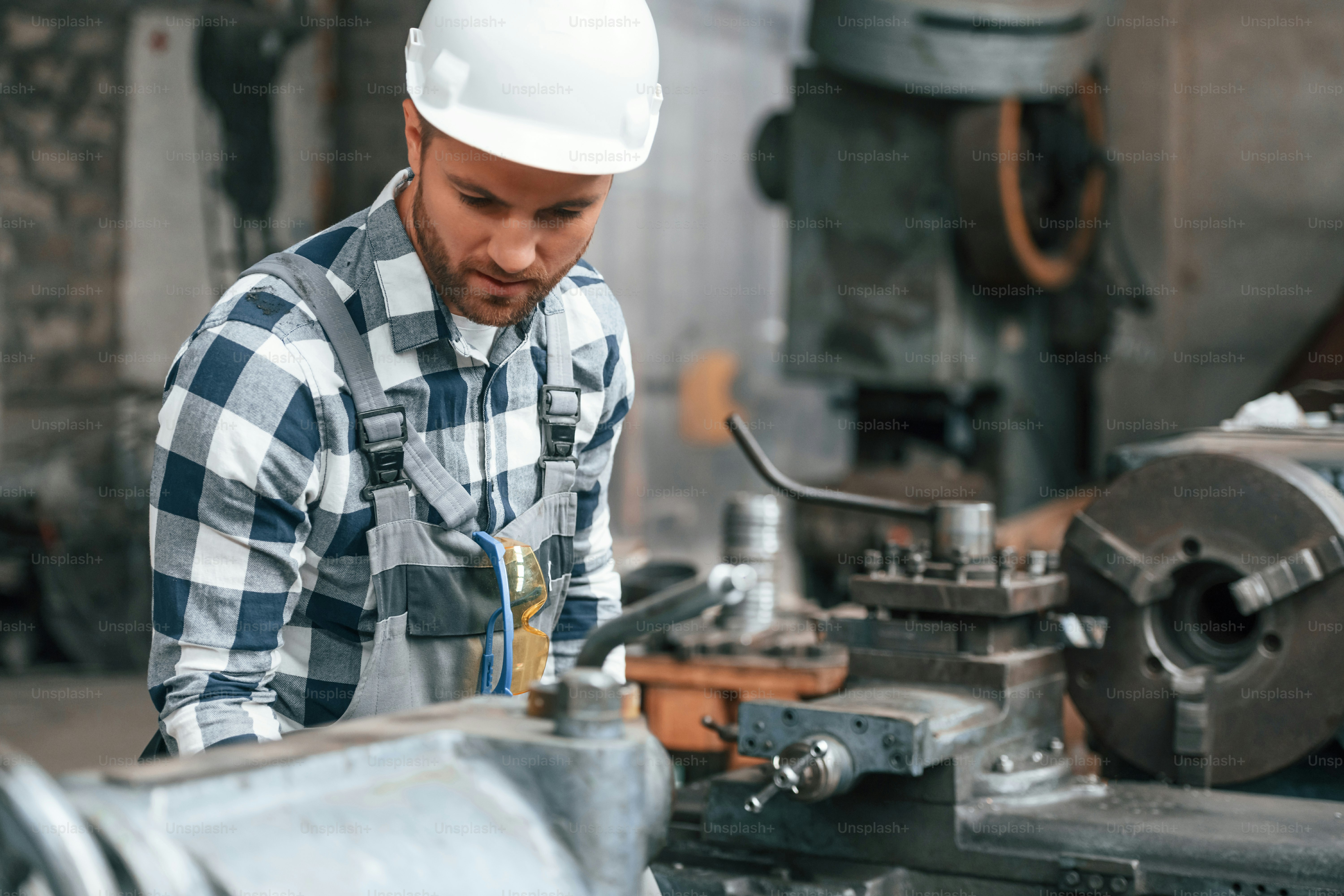 操作マシンによる作業。制服を着た工場労働者は屋内にいます。