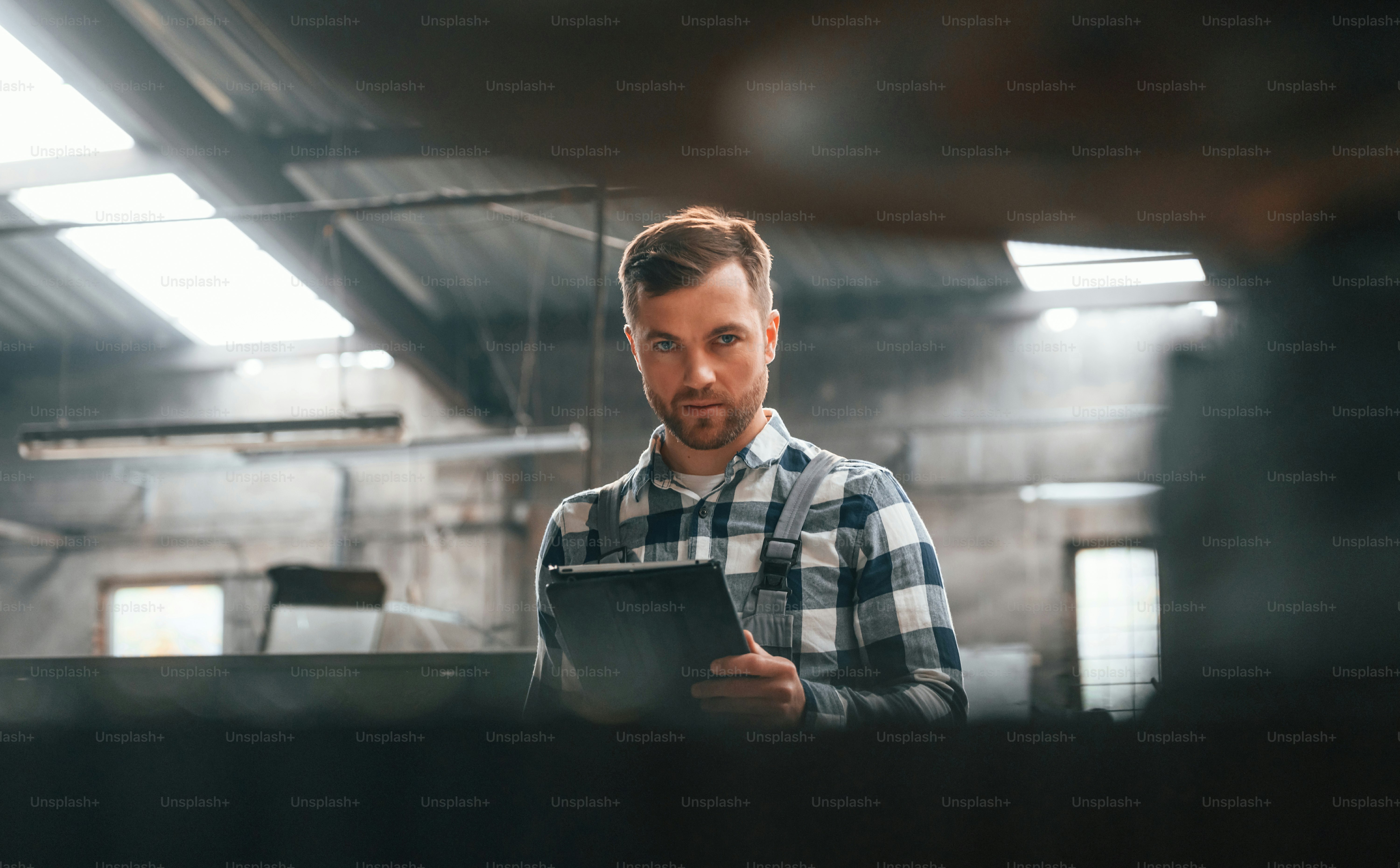 立ってグラフィックタブレットを使用する。制服を着た工場の男性労働者は屋内にいる。