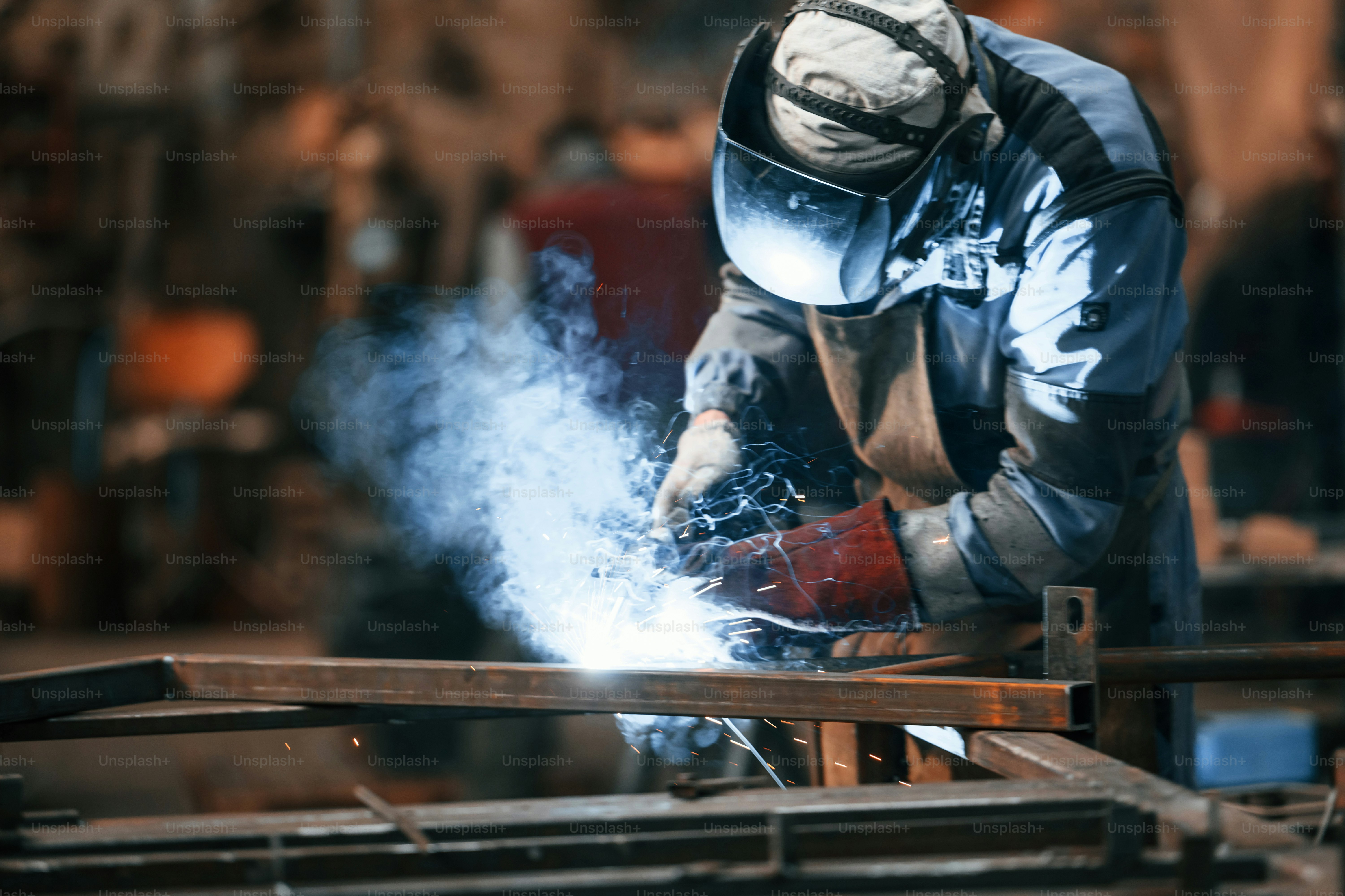 Close up view. Factory worker in protective mask is welding the iron.