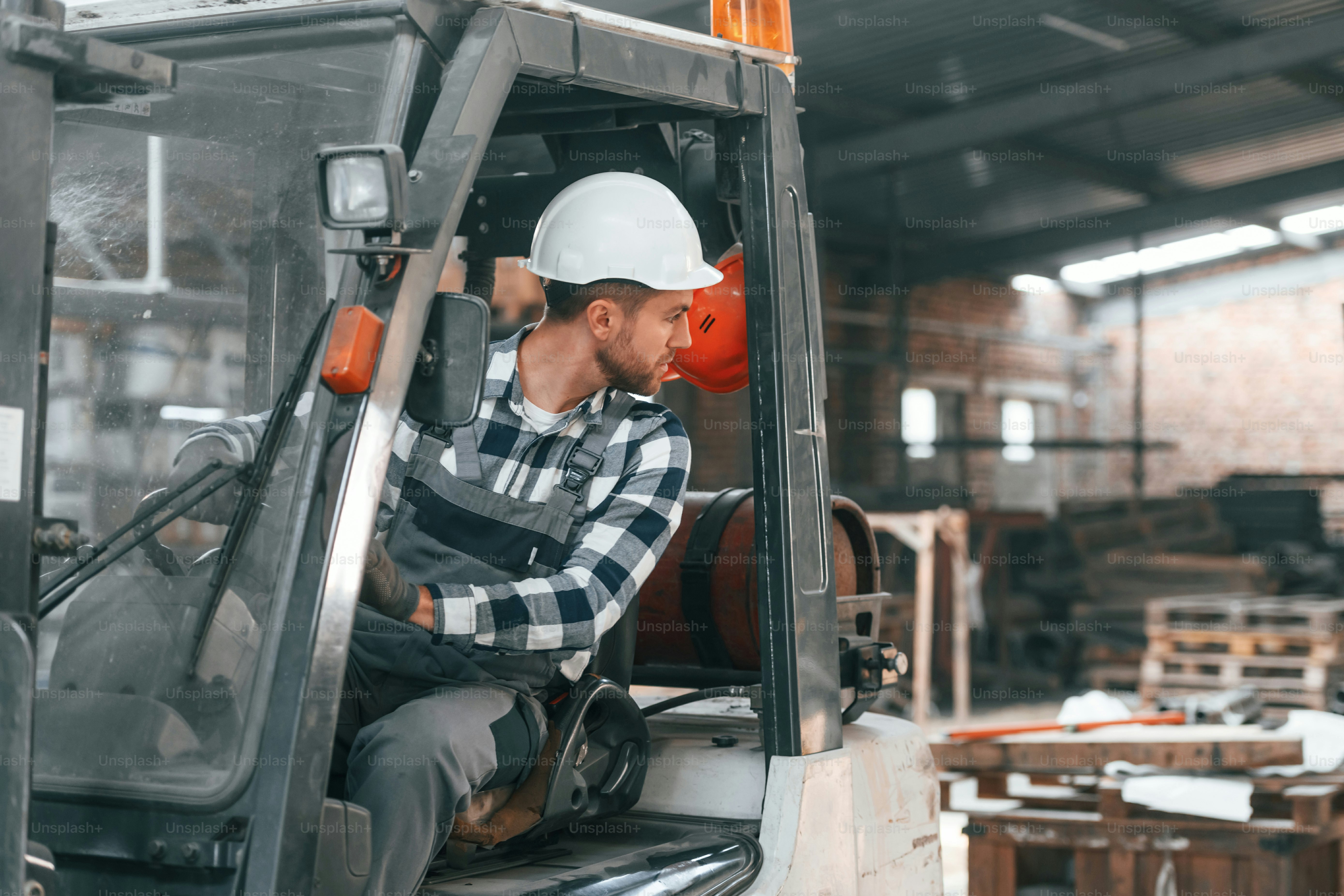 車両を運転する。制服を着た工場の男性労働者は屋内にいる。