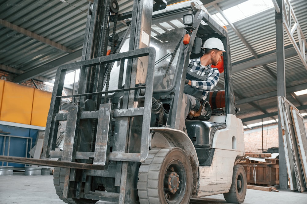 Inside of the forklift. Factory male worker in uniform is indoors.